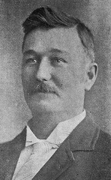 a man wearing a suit and bow tie is in black and white