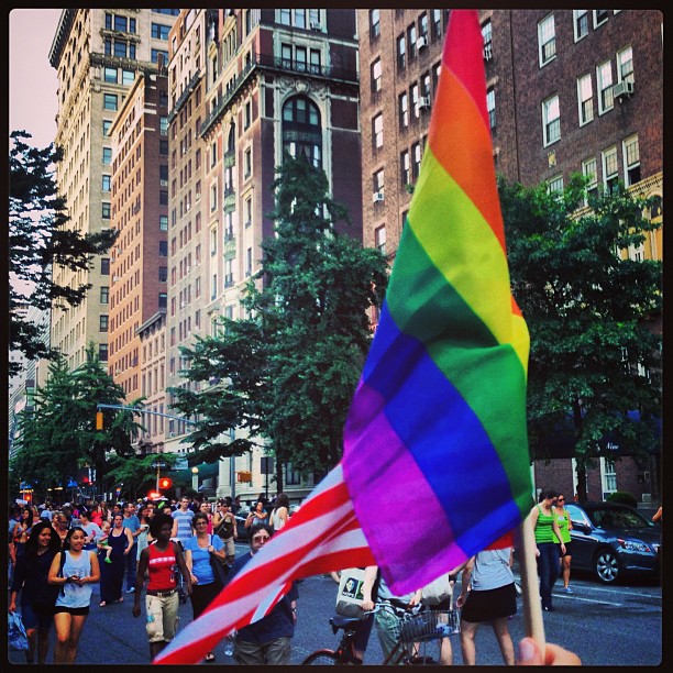 a large group of people are marching down the street with gay pride flags