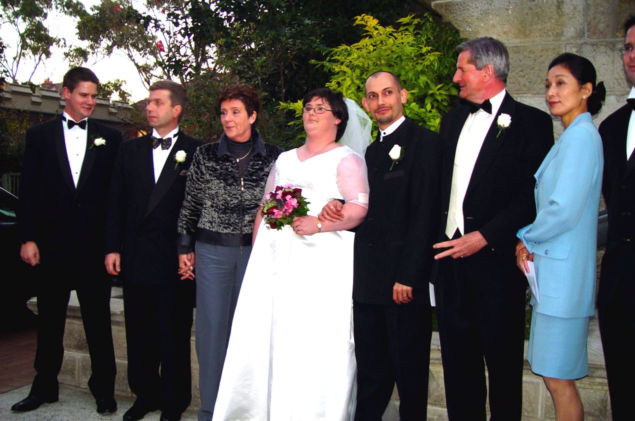 a bride and groom are standing with a group of friends