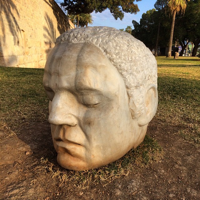 a statue of a man's face in front of trees