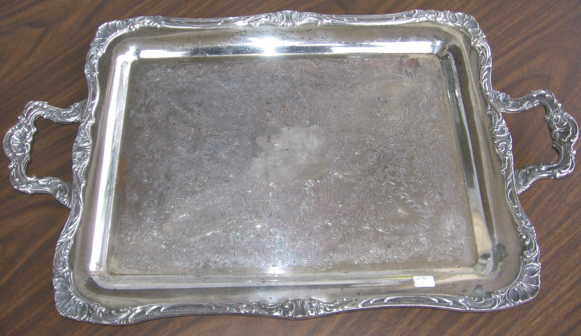 silver square tray with silver metal decoration sitting on wooden table