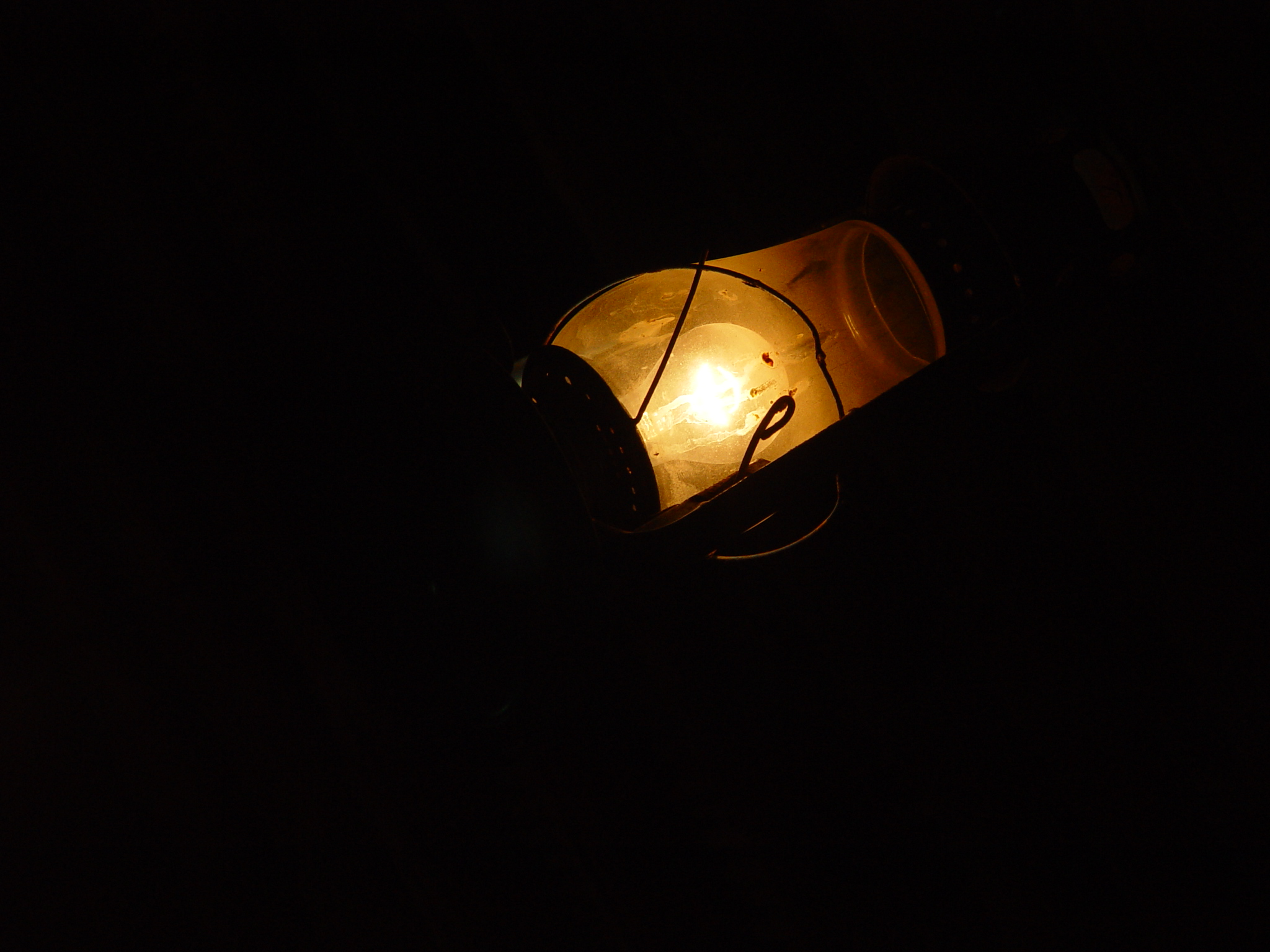 a lighted lamp in the dark on top of a wooden stand