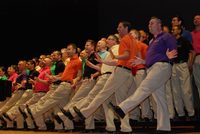 dancers stand in a line on stage and clapping