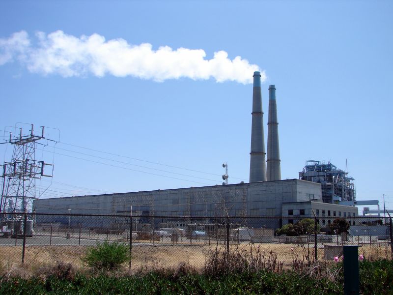 smoke rises from a factory building next to power lines