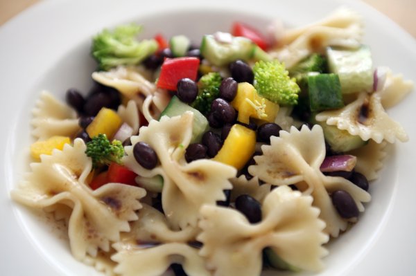 a white bowl filled with pasta, broccoli, and beans