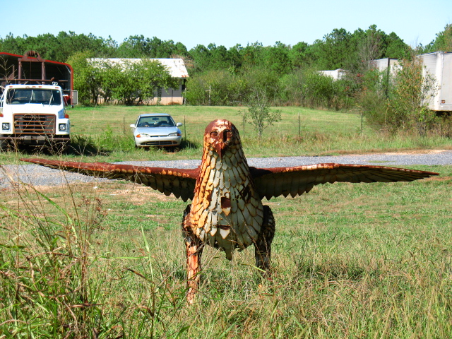 the large bird stands in the grass near a truck