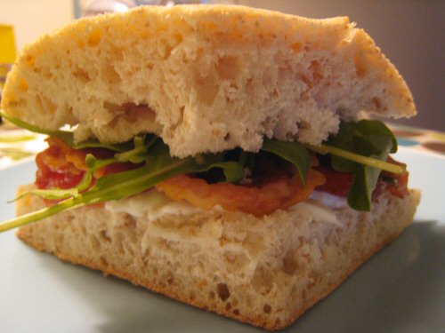 a sandwich with spinach leaves and tomato sauce