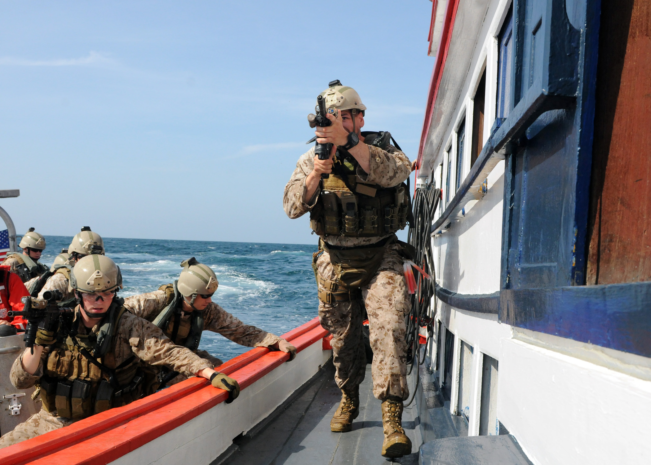 military men are moving along the water on a boat