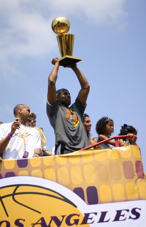 a man holds the los angeles lakers trophy above his head