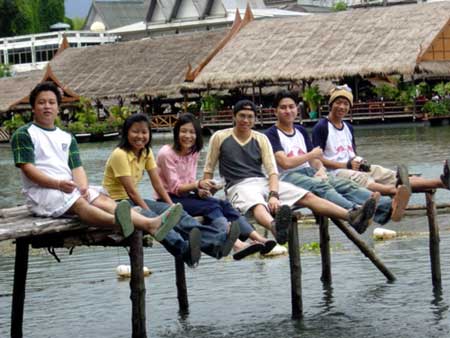 a group of people sitting on top of a bridge over water