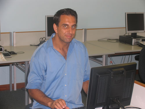 the man in blue shirt is looking at a computer monitor