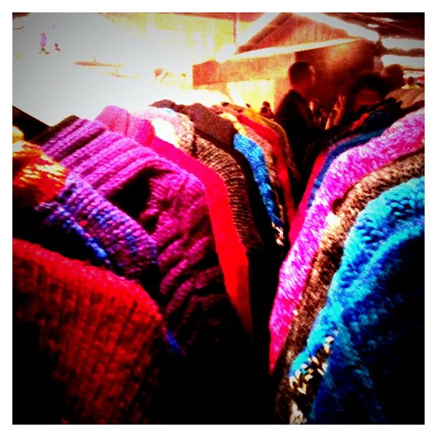 three different colored sweaters on display in a store