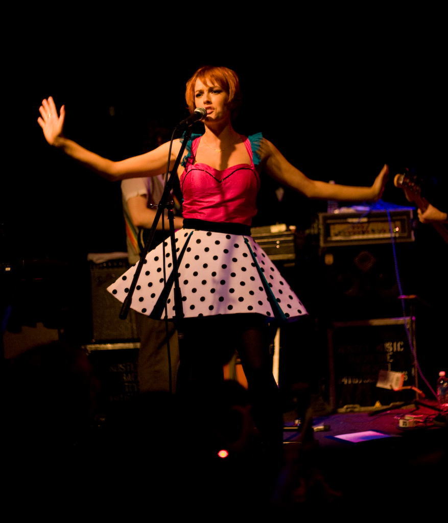 the woman is singing at a concert with her hands out