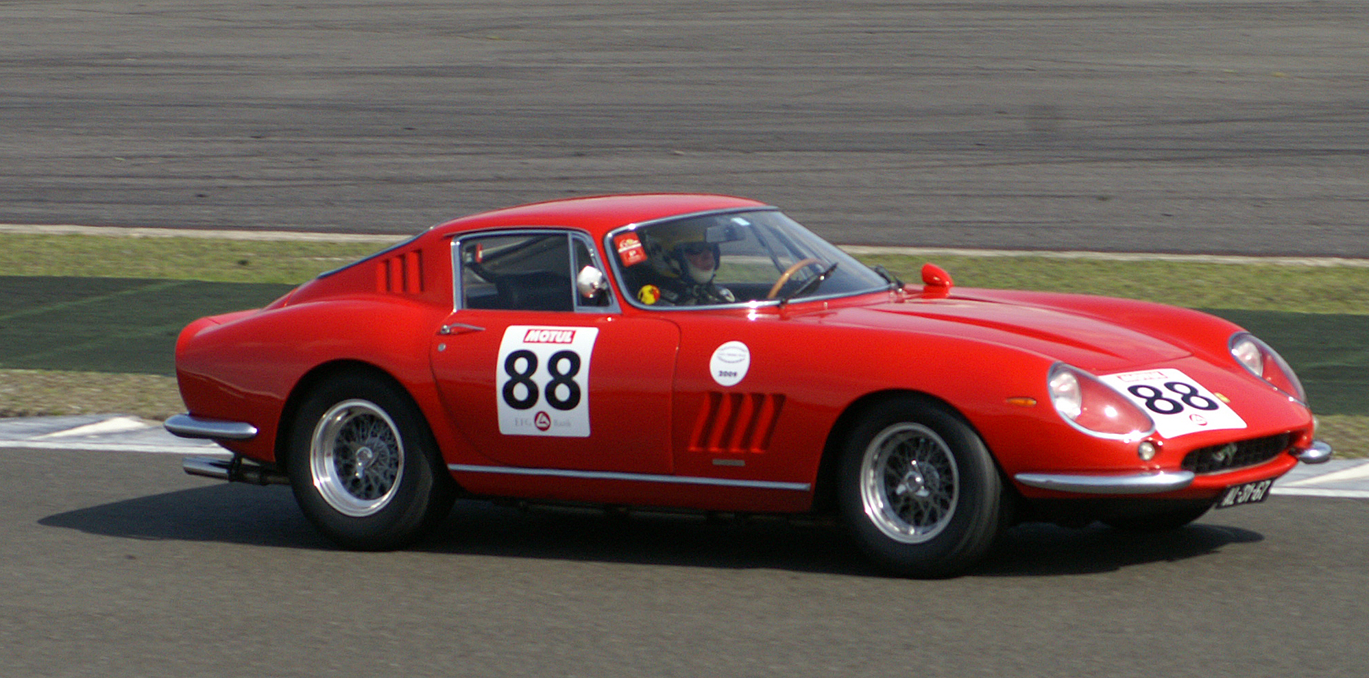 a red racing car in motion on a road