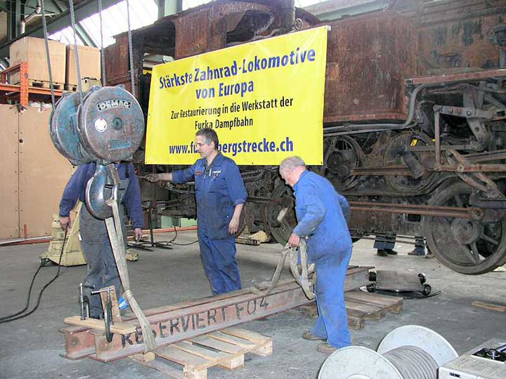 three men in blue work on a train