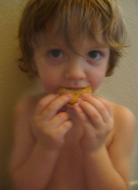 a little boy is eating some food in his hand