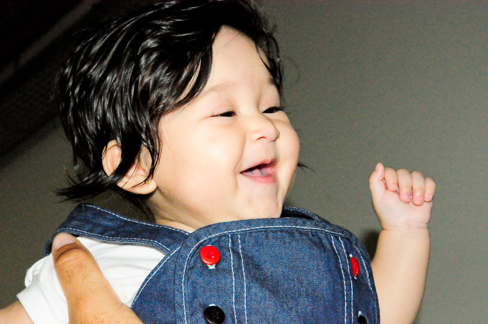 a little boy smiles and holds onto his finger