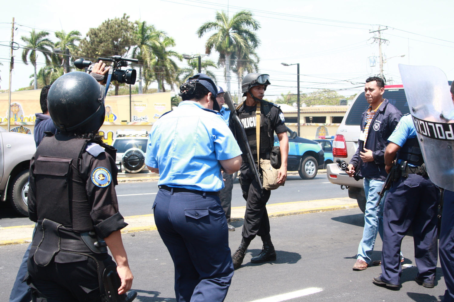 police officers with cameras and a man holding a sign on the street