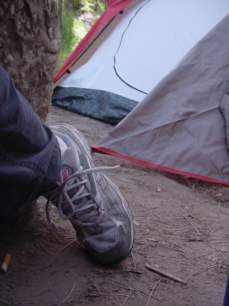 a person standing next to a tent, wearing sneakers