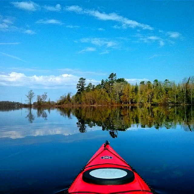 a red kayak floats on a calm lake