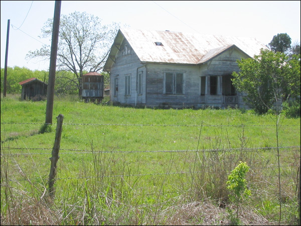 an old run down, run down farmhouse sits in a grassy field