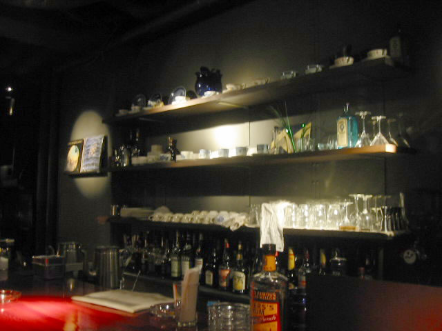 bottles are lined up along the wall of this dimly lit bar