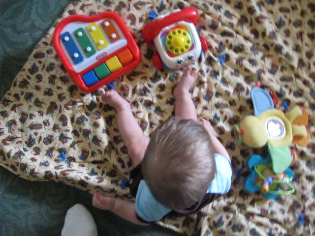 the toddler has toys laying on the floor