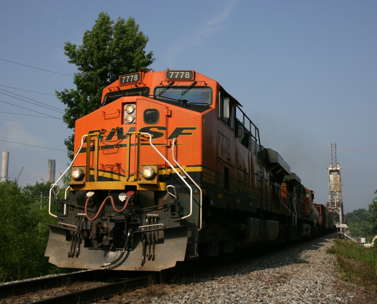 a large train on a steel track near a forest