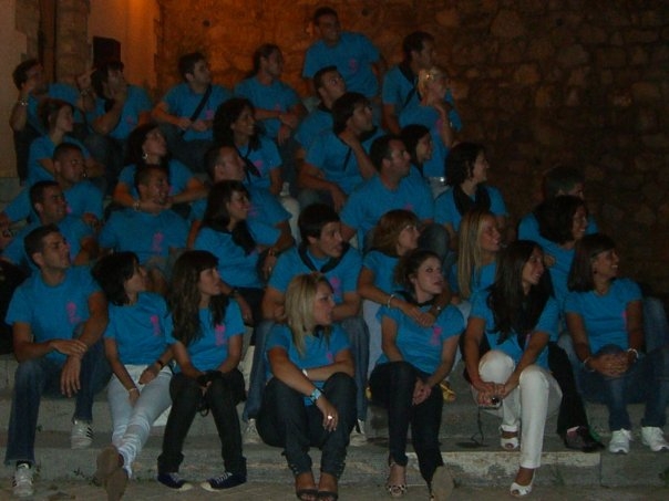 a group of people are sitting on steps, some in blue shirts