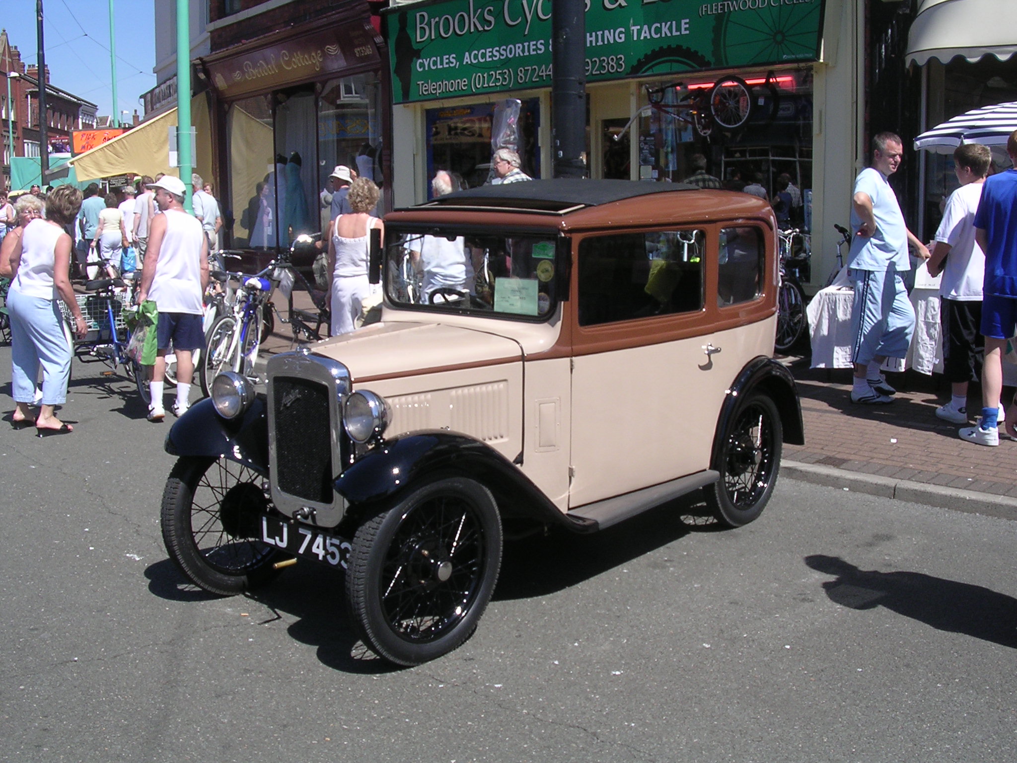 an antique car parked on the street in front of a group of people