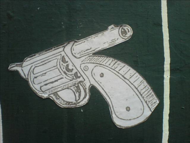 an old sticker depicting a gun pointing at soing
