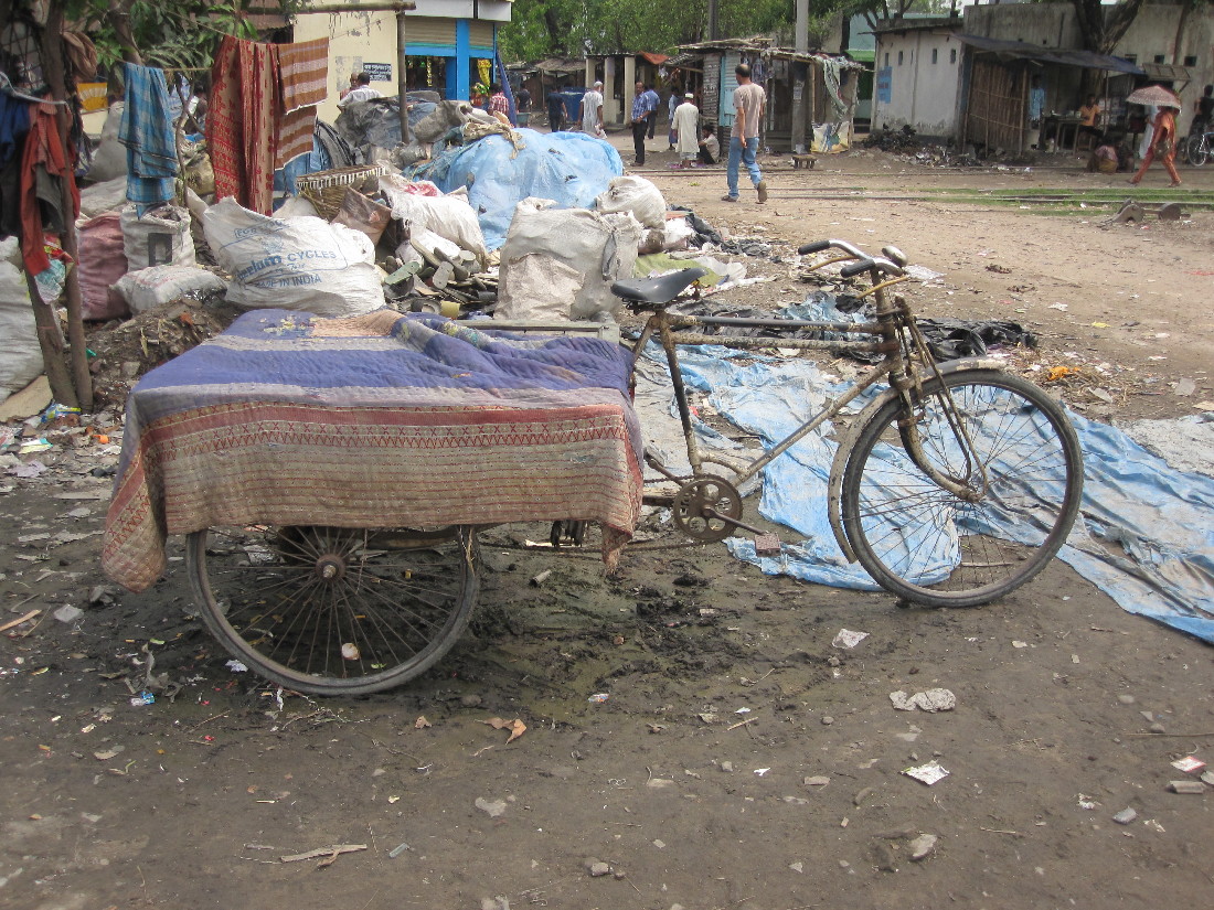 a bicycle leans against a covered picnic table in an impoverished area