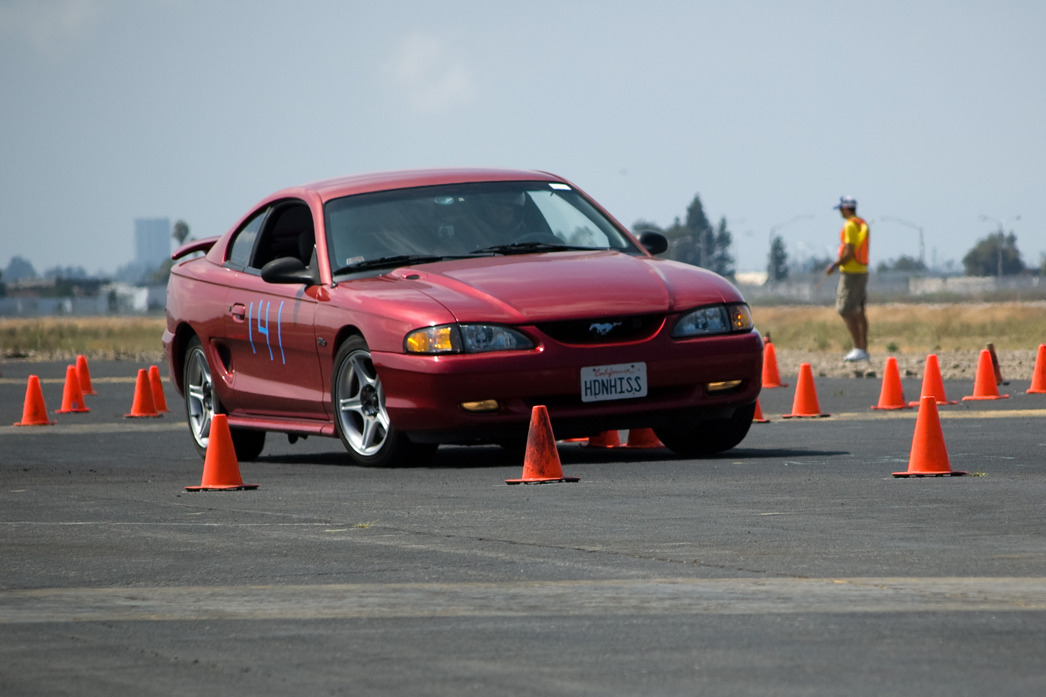 a red mustang is sitting next to a road cone set