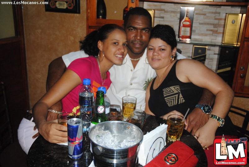 three adults are standing around a table with beverages