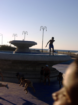 two men riding skateboards on top of a large water fountain