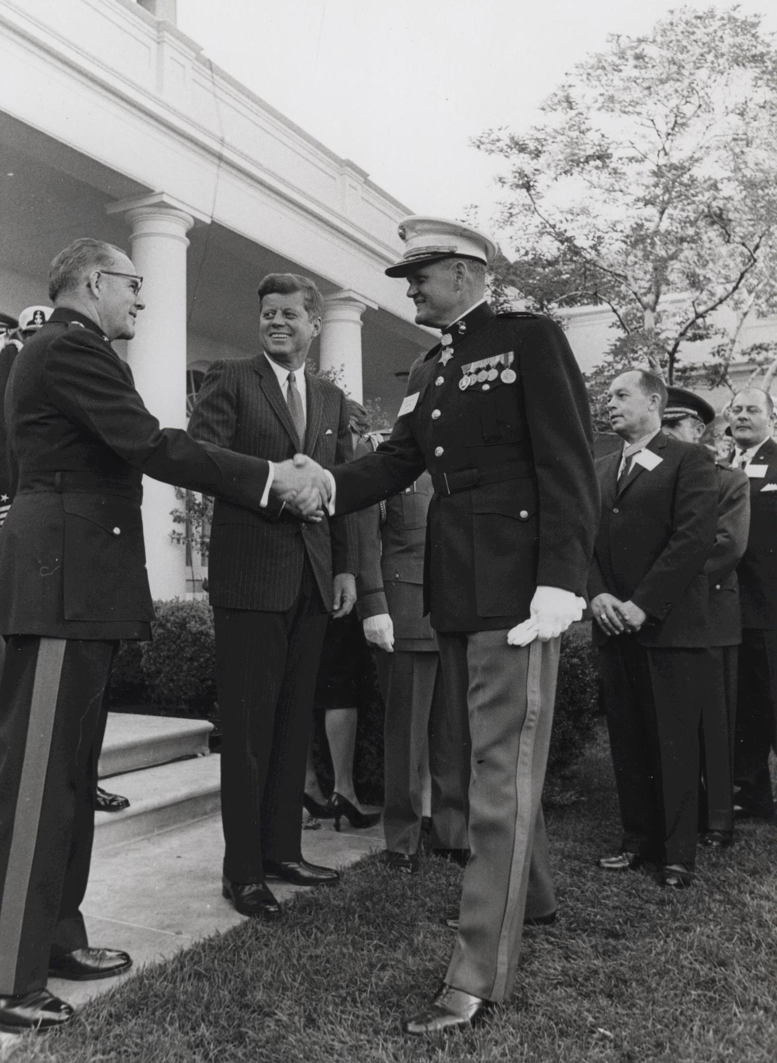 some men in military uniforms shaking hands in front of a building