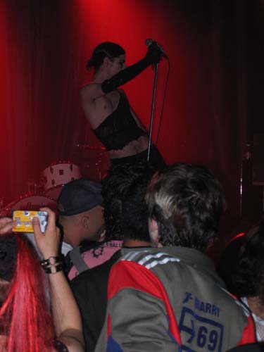 a woman in tight clothing stands on top of a man in a concert