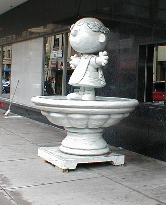 a statue of a boy holding a umbrella is on the sidewalk