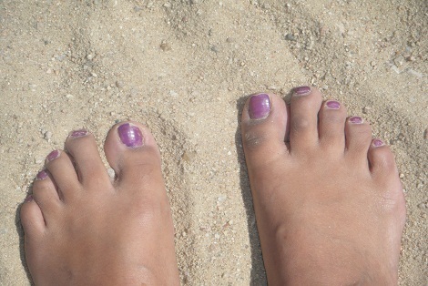 a person with purple fingernails on sand in the dirt