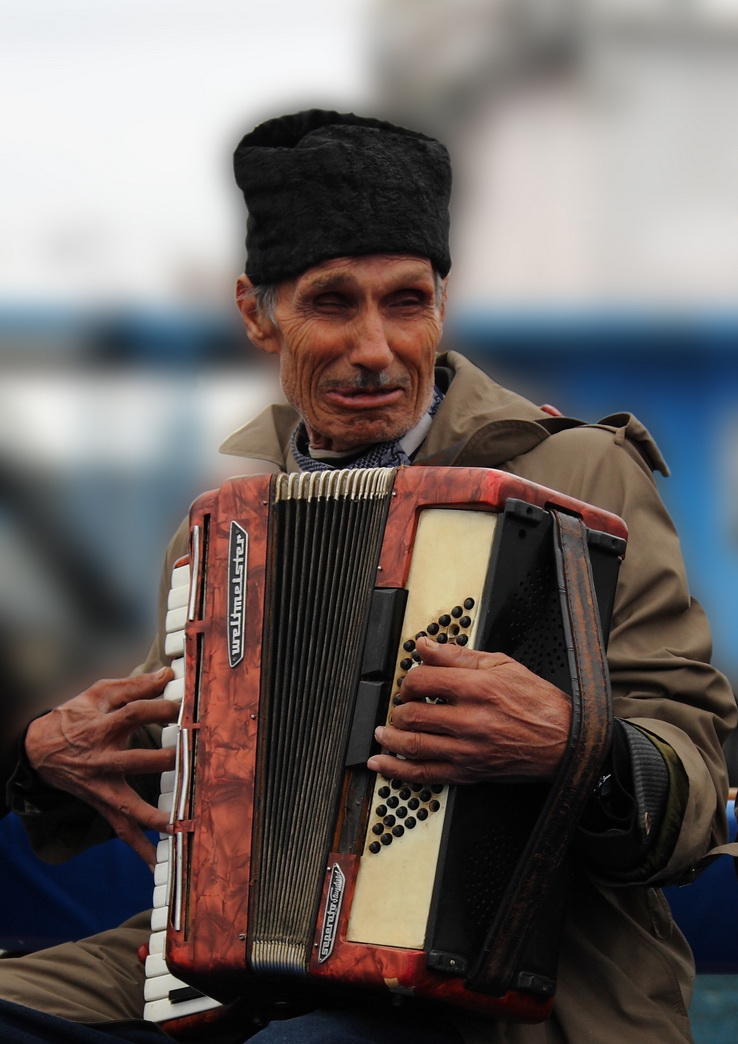 an old man is sitting and playing an accordion