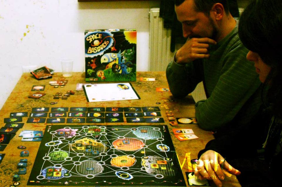 a couple sit at a table with a board game set up