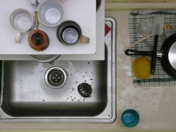 a view of a kitchen sink with dishes on the counter and the lid down
