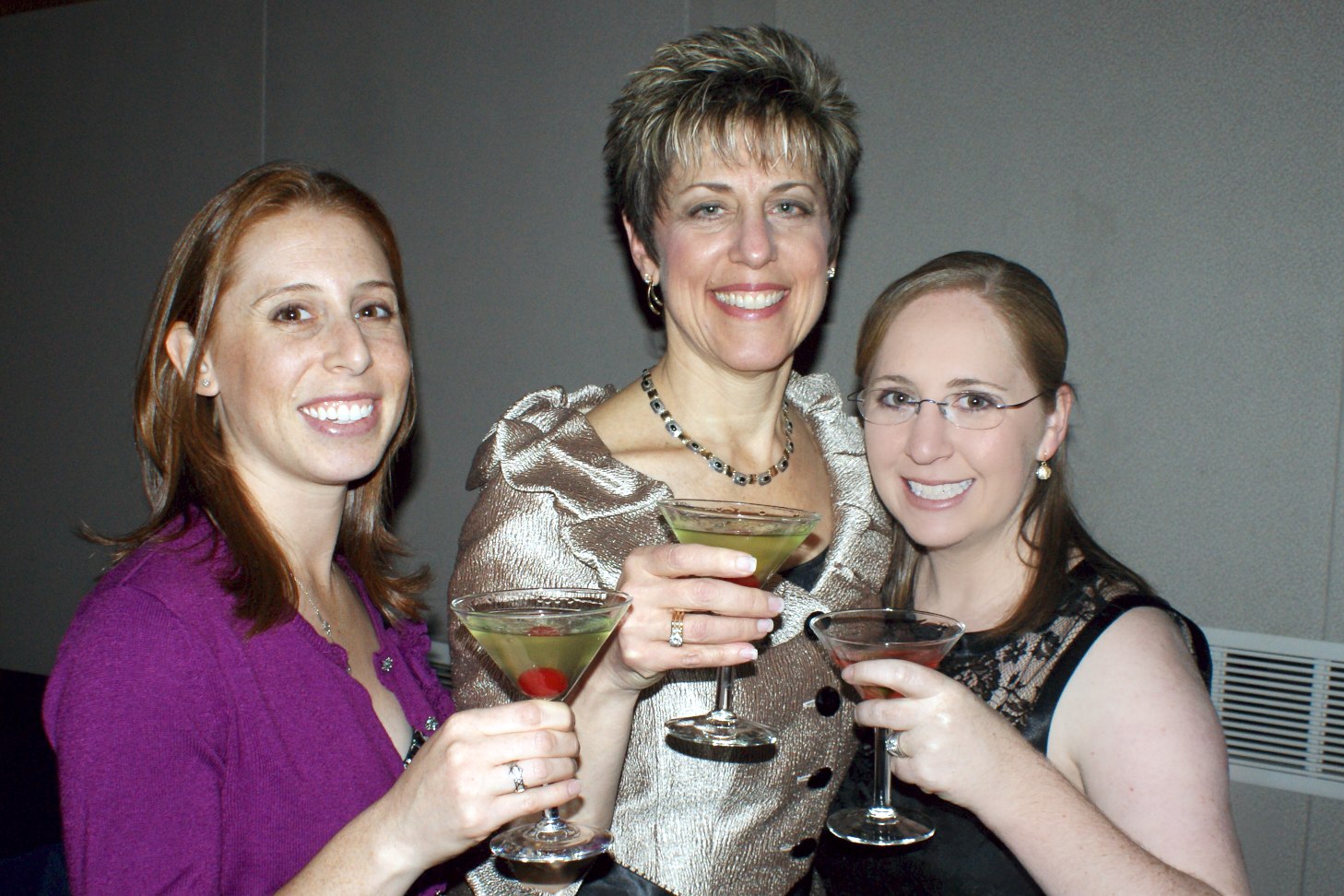 two women and one girl are smiling while holding martinis