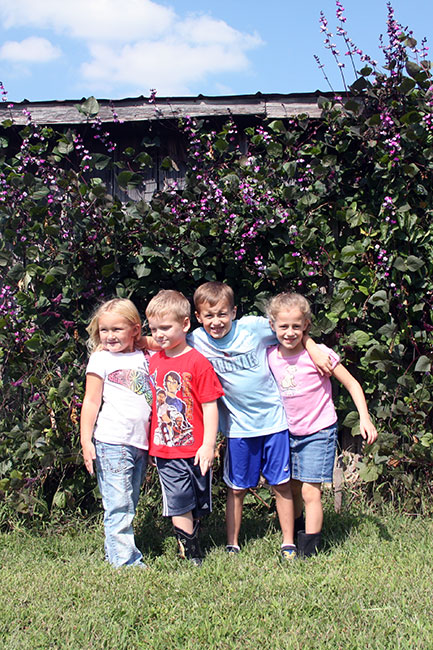 a group of s stand near a bush full of purple flowers