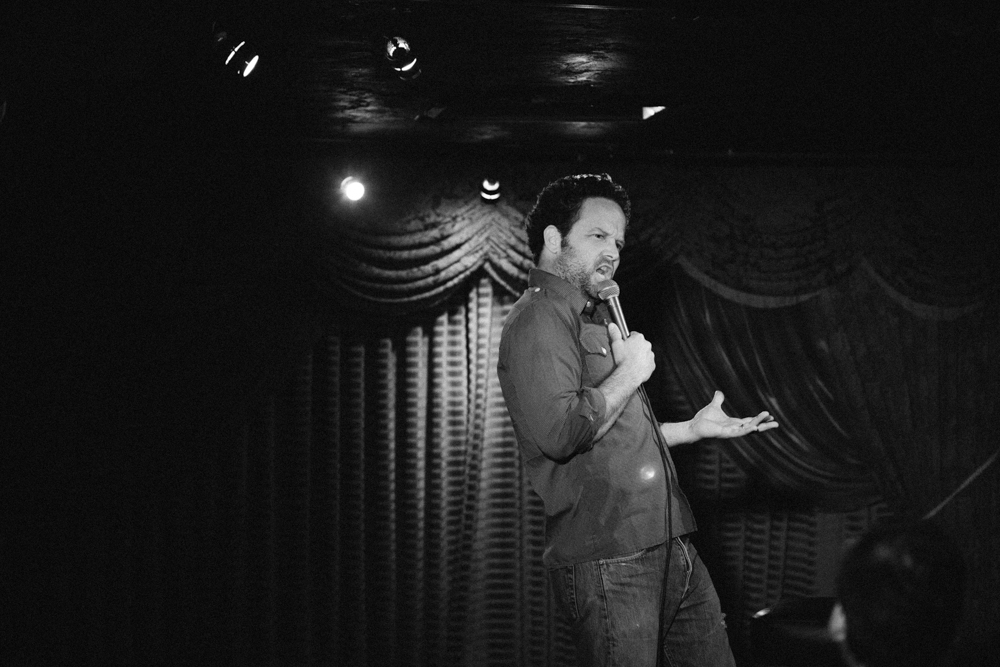 a man holding a microphone stands near a curtain