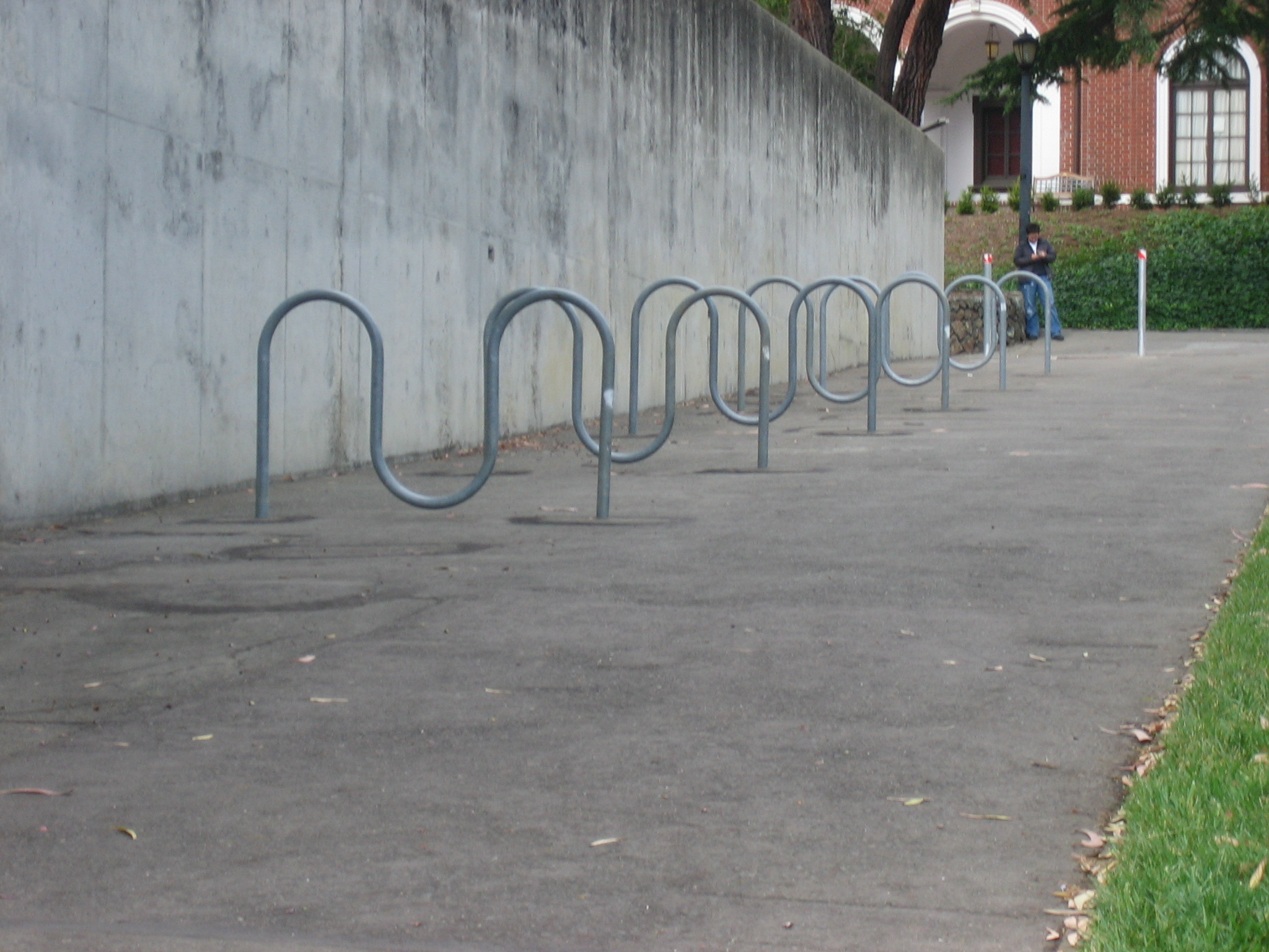 the line of bars on the sidewalk is empty and the people are sitting outside