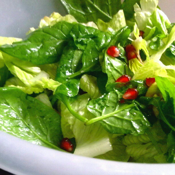 green salad with red peppers in a white bowl