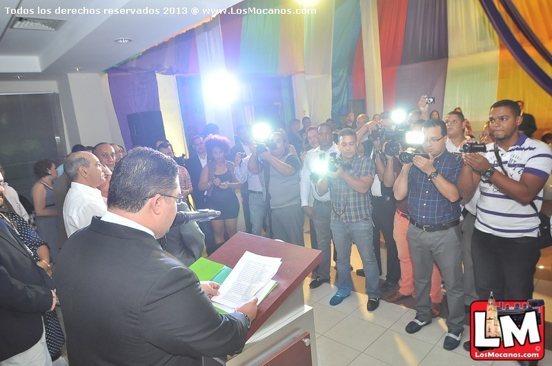 man taking pictures of a man in a suit holding a book and standing with other people taking pos