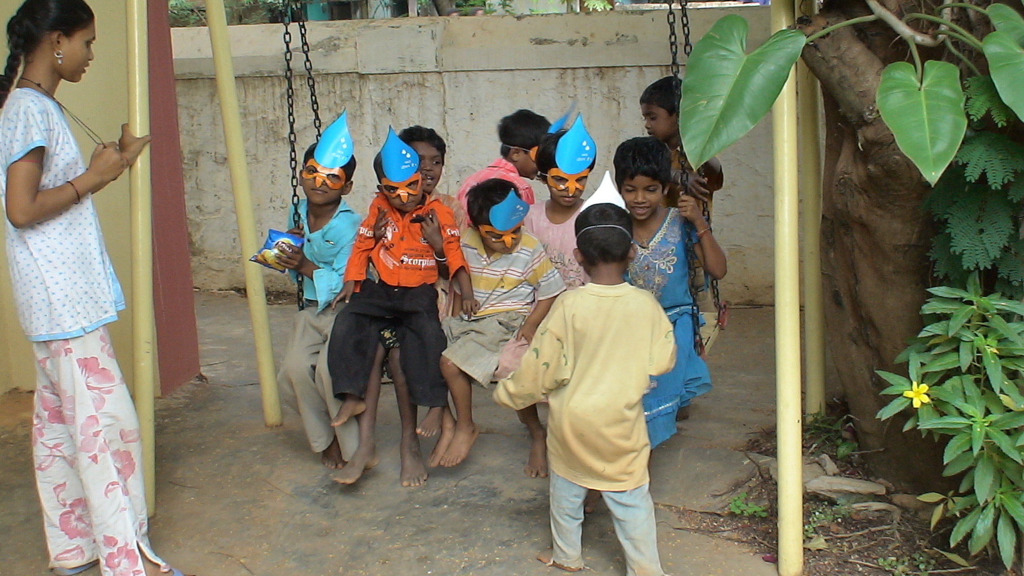 a group of s are on a swing with paper party hats