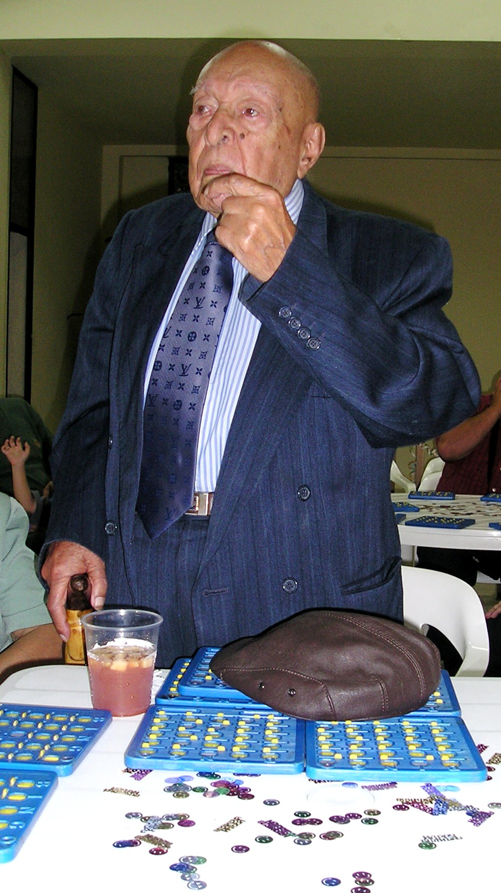 an old man with his fingers on his mouth is standing in front of several paper table decorations